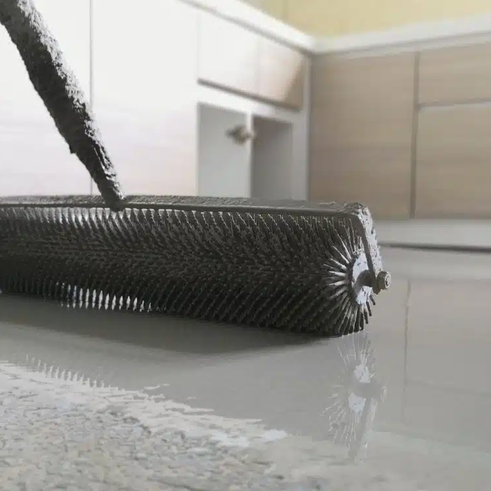 Spiked roller applying epoxy coating, highlighting the lengthy dry time required compared to modular flooring.